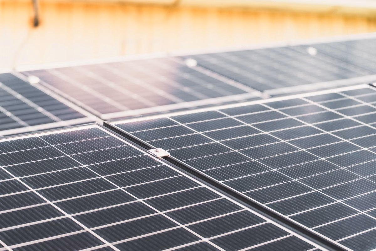 Close-up of rows of solar photovoltaic panels fixed side by side with metal clamps.